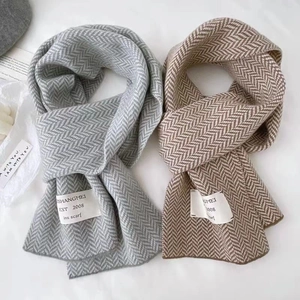 Détail d'écharpes en tricot à chevrons gris et marron avec des étiquettes minimalistes