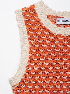 Macro shot of sleeveless knitted dress with orange hollow-out texture and rib edge