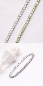 Macro detail of tennis bracelets with zircon gemstones in blue, gold, and purple tones