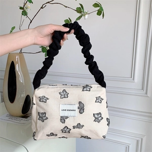 Detail of canvas tote bag with black ruffle handle and artistic patterns