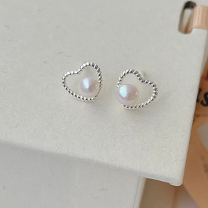 Macro detail of heart-shaped freshwater pearl earrings with silver twisted rope texture