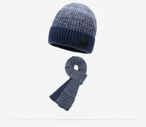 Dettaglio del set cappello e sciarpa in maglia blu scuro con fodera in pile e logo in pelle