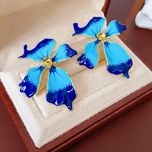 Macro shot of vintage gradient blue enamel flower earrings with gold edges in a jewelry box