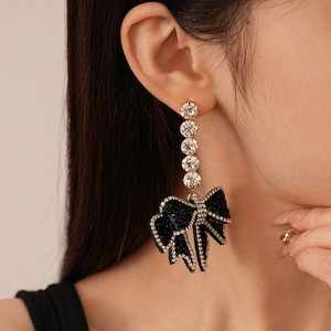 Close-up of black bow earrings with sparkling crystals worn by a female model