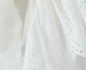 Vue macro du tissu brodé blanc avec détails de bordure festonnée pour robe d'été légère