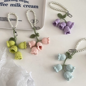 Detailed macro view of colorful crochet lily of the valley flowers with pearl handles