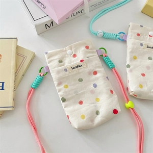 Polka dot canvas crossbody bag with pink woven strap and Sozakka label on a book
