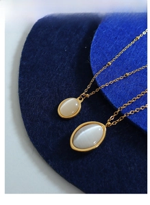 Detailed close-up of vintage oval cat-eye stone pendants on a gold titanium steel necklace