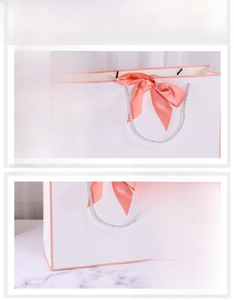 Close-up of white gift bag with pink ribbon bow and durable silver woven handles
