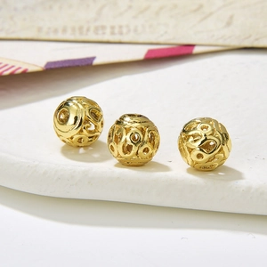 Macro detail of three vintage gold hollow round beads with intricate floral patterns