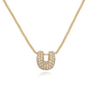 Macro detail of U-shaped gold pendant necklace with cubic zirconia paving on white surface