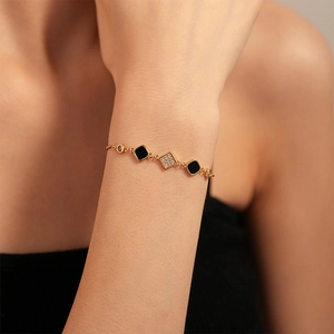 Detailed macro view of gold-plated bracelet with black square charms and cubic zirconia