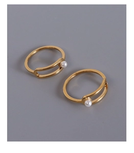 Detail of geometric gold-plated steel rings with minimalist lines and faux pearl accents
