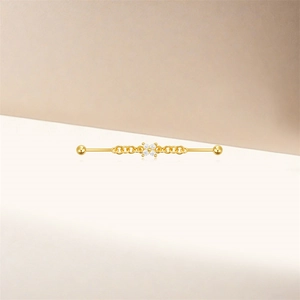 Close-up of golden industrial barbell with sparkling flower zircon and delicate chain link