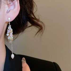 Close-up of long tassel earrings with crystals and pearls worn by a model in black suit