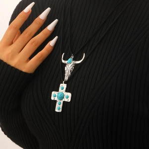 Detail of western cow skull and turquoise cross pendant on black cord necklace