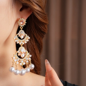 Macro detail of luxury fan-shaped tassel earrings with pearls and gold crystals