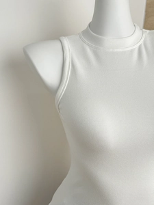Detailaufnahme der weißen Rippstrick-Textur und des weichen Stoffs des ärmellosen Tops
