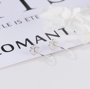 Macro detail of cat paw silver earring hooks on elegant white background with floral decor