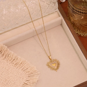 Detailed view of a golden heart sunburst pendant on a beige velvet jewelry tray