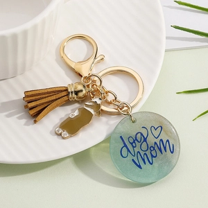 Detail of dog mom resin keychain with golden puppy charm and brown tassel on white tray