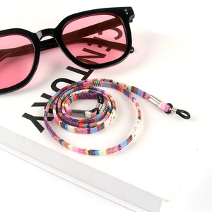 Close-up of bohemian woven eyewear strap with metal fasteners on a white book