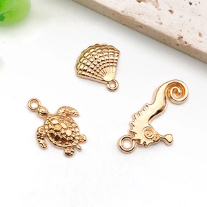 Makroaufnahme von KC-Gold-Meeresanhängern wie Schildkröte und Muschel für DIY-Schmuck