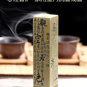 Macro shot of gold brass incense burner with engraved Heart Sutra text and smoke
