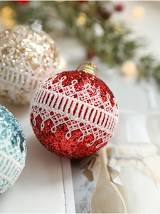 Close-up of a red Christmas foam ball with glitter and white lace trim on a tree