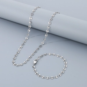 Close-up of silver coffee bean link necklace and bracelet set on a minimalist pedestal