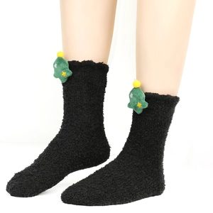 Detail einer schwarzen Korallenvlies-Socke mit grünem 3D-Plüsch-Weihnachtsbaum-Dekor