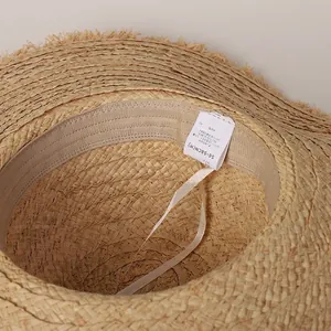 Handmade oversized raffia straw beach hat with frayed edges and adjustable inner band