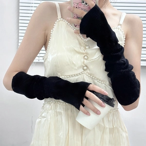 Detailed view of long black knitted fingerless arm sleeves styled with a light dress