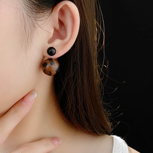 Close-up of a model wearing leopard print ball earrings with a sleek black stud
