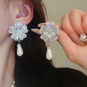 Detail of silver floral earrings with sparkling crystals and a teardrop pearl drop
