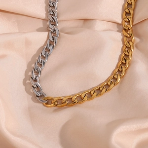 Dettaglio della collana a catena cubana bicolore 8mm oro e argento su seta color champagne