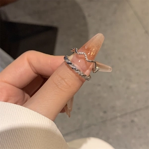 Close-up of a silver twisted zircon ring set and wave band worn on a finger