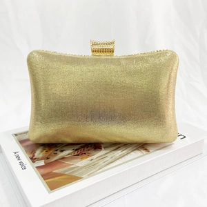 Detail of elegant gold glitter clutch bag showing metallic texture and ornate top clasp