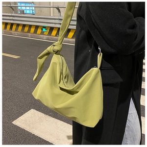 Detail of green nylon crossbody bag showing the large capacity and knot shoulder strap design