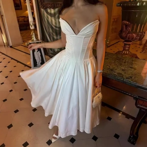 Detail of white satin dress featuring corset boning and elegant pleated maxi skirt