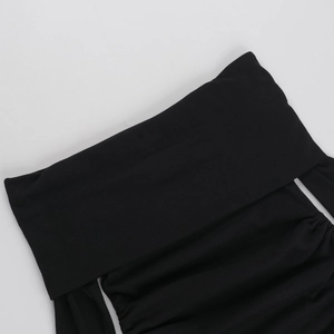 Dettaglio dell'abito nero in maglia a coste con spalle scoperte e coulisse laterale