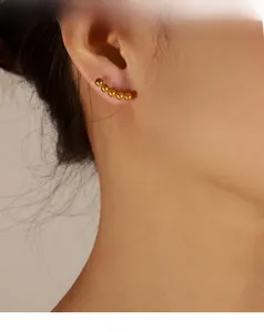 Detailed view of curved gold bead climber earrings showing elegant metallic finish