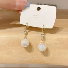 Close-up of gold pearl drop earring with small crystal accent on jewelry card
