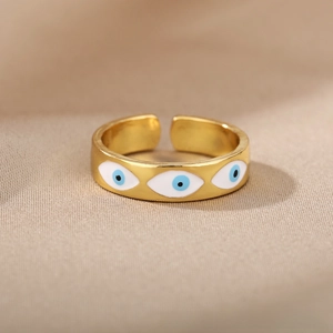 Macro shot of gold adjustable open ring featuring three blue evil eye charms on fabric