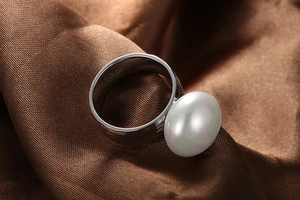 Macro shot of an oval white pearl set on a thick silver stainless steel ring band