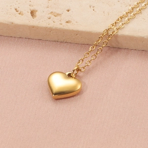Détail du pendentif cœur 3D doré sur chaîne fine avec fond en soie et pierre naturelle