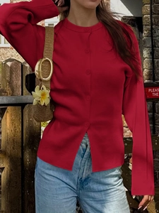 Détail d'un cardigan en maille rouge boutonné porté avec un jean bleu décontracté
