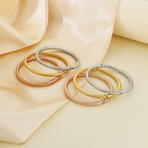 Detail of twisted and diamond-cut textured bangles in gold, silver, and rose gold