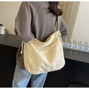 Detail of minimalist cream canvas tote bag with front pocket carried by a person
