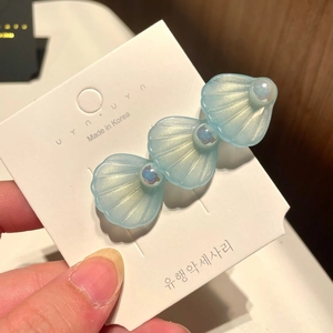 Detail of light blue resin shell hair clip with iridescent pearls on display card